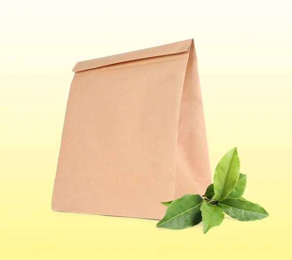 Paper bag and green leaves on light background. Eco friendly lifestyle