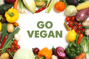 Phrase Go Vegan and fresh vegetables on white background, flat lay