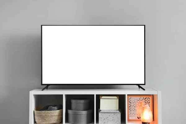 Modern TV on cabinet near light wall indoors. Interior design