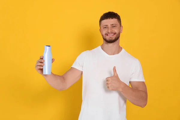 Handsome Young Man Holding Bottle Shampoo Orange Background —  Fotos de Stock