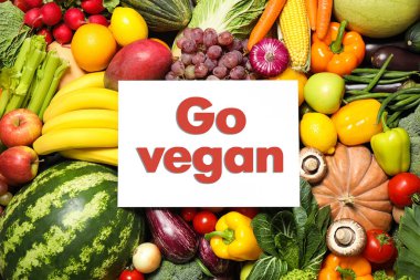 Paper card with phrase Go Vegan, fresh vegetables and fruits, top view