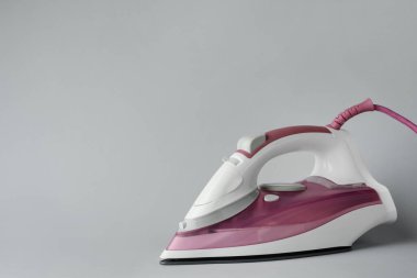 Açık gri arka planda modern bir ütü, metin için boşluk. Ev aletleri