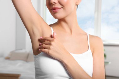 Young woman showing smooth skin after epilation indoors, closeup