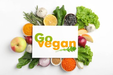Kağıt kartın içinde Go Vegan ve beyaz arka planda taze ürünler, düz yatış