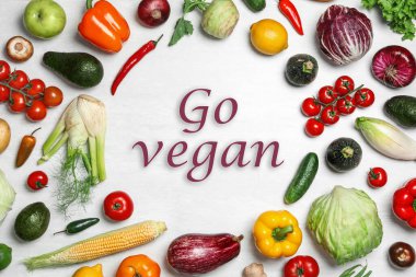 Phrase Go Vegan and fresh vegetables on white background, flat lay