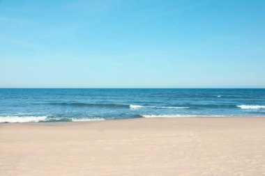 Güneşli bir günde güzel deniz ve kumlu plaj manzarası.
