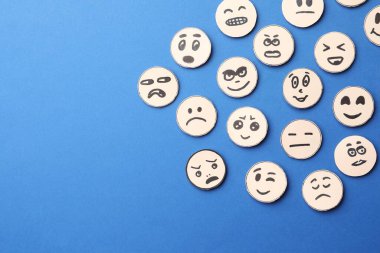 Many faces with different emotions on blue background, flat lay. Space for text