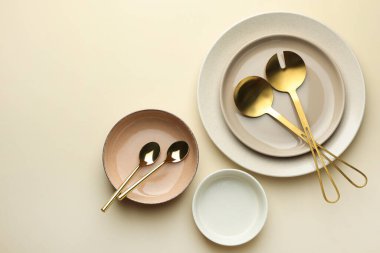 Stylish empty dishware and cutlery on beige background, flat lay