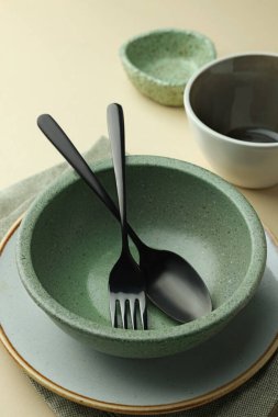 Bej arka planda boş bulaşık takımı ve çatal bıçak takımı, yakın plan