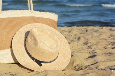 Güneşli bir günde deniz kenarında şık bir çanta ve şapka, yazı için yer. Plaj aksesuarları