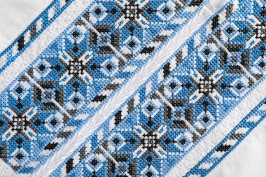 Beautiful light blue Ukrainian national embroidery on white fabric, top view