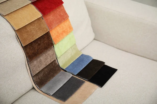 Catalog of colorful fabric samples on beige sofa