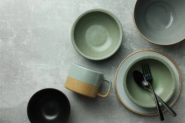 Boş bulaşık takımları ve çatal bıçaklar açık gri masada, düz yerde.