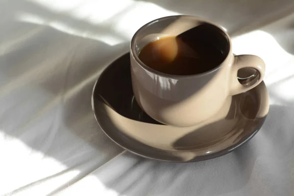 Cup of aromatic coffee on bed in morning, closeup