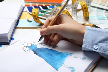 Moda tasarımcısı masada elbise çiziyor, yakın plan.