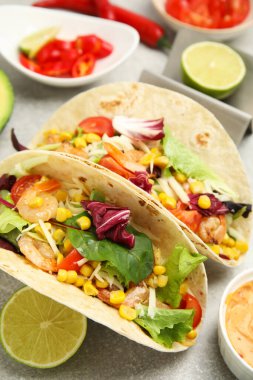 Açık gri masada karidesli ve limonlu lezzetli tacolar, yakın plan.