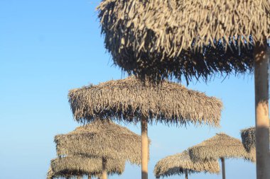 Mavi gökyüzüne karşı güzel saman plaj şemsiyeleri