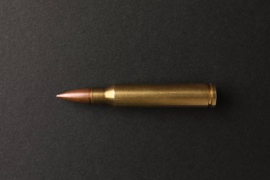 One bullet on black background, top view