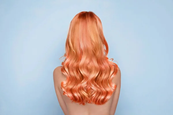 Beautiful woman with long orange hair on light blue background