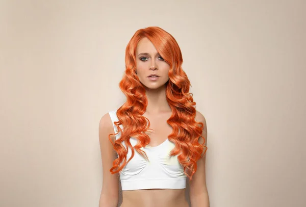 Beautiful woman with long orange hair on beige background