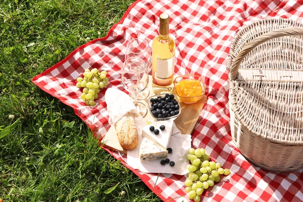 Picnic blanket with delicious food and wine outdoors on summer day