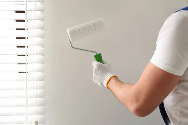 Man painting wall with white dye indoors, closeup