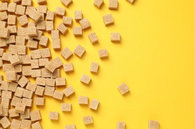 Sarı arka planda kahverengi şeker küpleri, düz uzanmış. Metin için boşluk