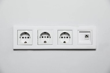 Beyaz duvarda elektrik prizleri var. Elektrik arzı