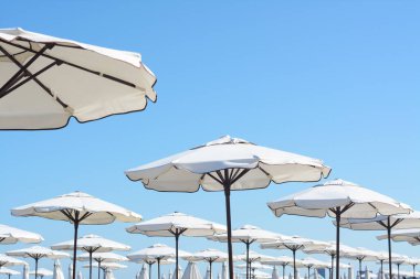 Beautiful white beach umbrellas against blue sky