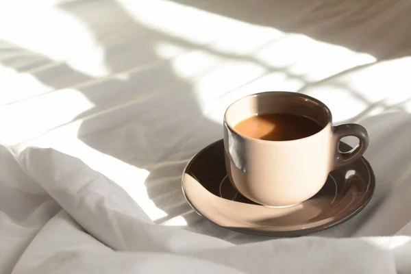 Cup of aromatic coffee on bed in morning, space for text