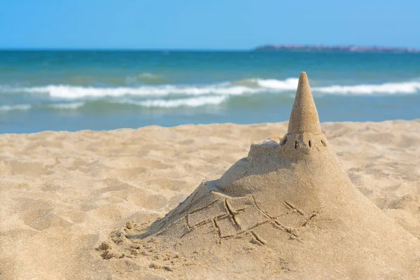 Beach with sand castle near sea on sunny day. Space for text