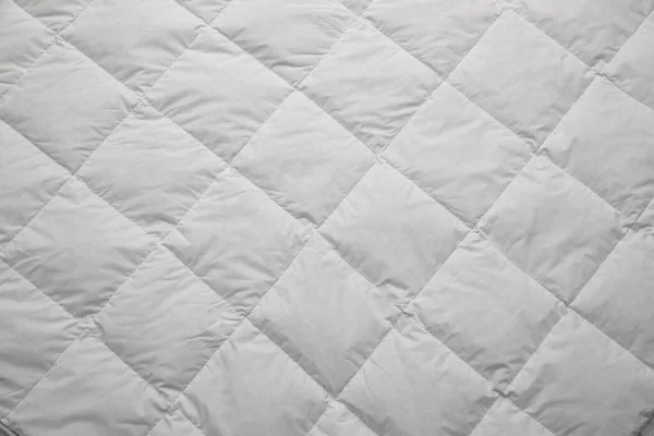 Soft quilted blanket as background, top view