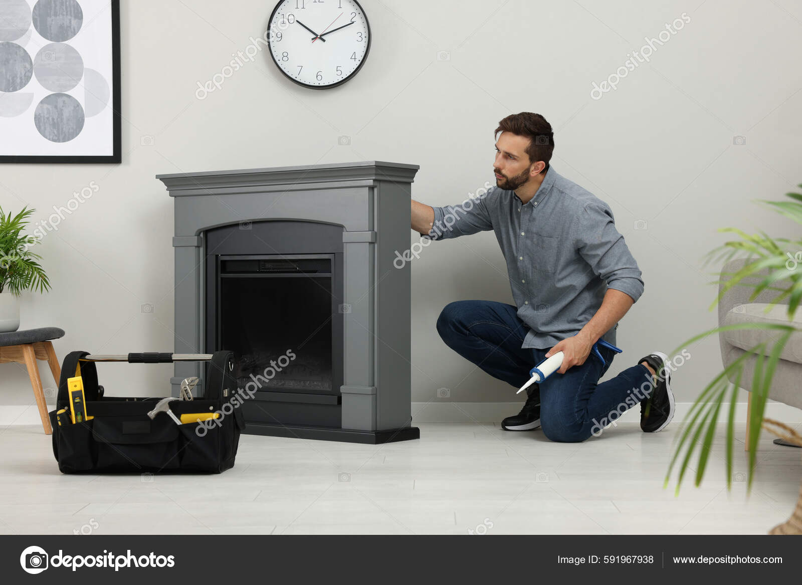 Man Sealing Electric Fireplace Caulk Wall Room Stock Photo by