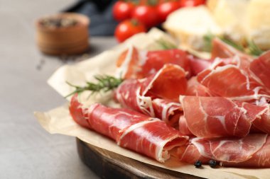 Gri masada lezzetli prosciutto dilimleri, yakın plan.