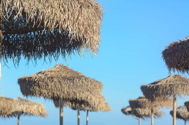 Mavi gökyüzüne karşı güzel saman plaj şemsiyeleri