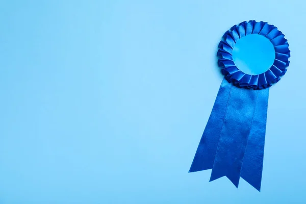 Blue award ribbon on turquoise background, top view. Space for text
