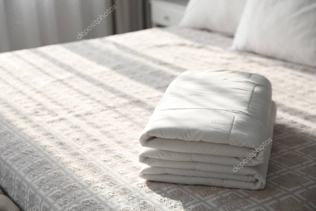 Folded clean blanket on bed in room. Space for text