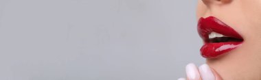 Açık gri arkaplanda kırmızı dudakları olan güzel bir kadın, yakın plan görüntüsü ve yazı için yeri olan bir kadın. Pankart tasarımı