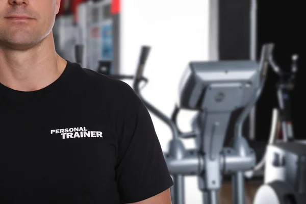 Professional personal trainer in gym, closeup. Space for text