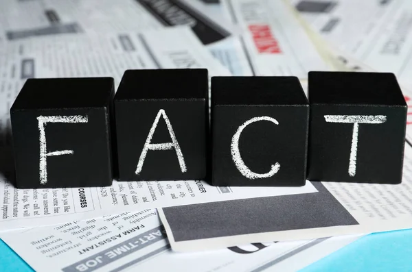 Word Fact Made Black Cubes Many Newspapers Light Blue Background —  Fotos de Stock