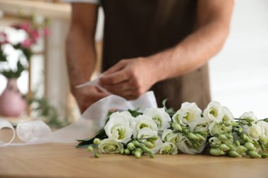 Çiçekçi atölyede güzel bir buket yapıyor, yakın plan.