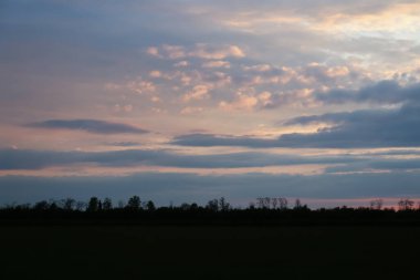 Gün batımında güzel kırsal manzaranın resmi.