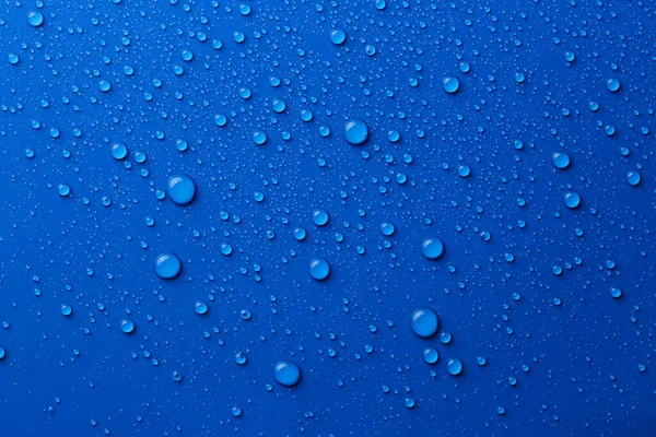 Water drops on blue background, top view