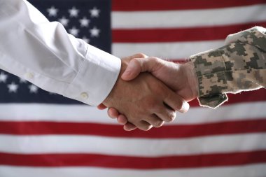 Asker ve işadamı ABD bayrağına karşı el sıkışıyor.