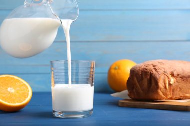 Sütü bardağa ve taze keki mavi ahşap masaya dök.