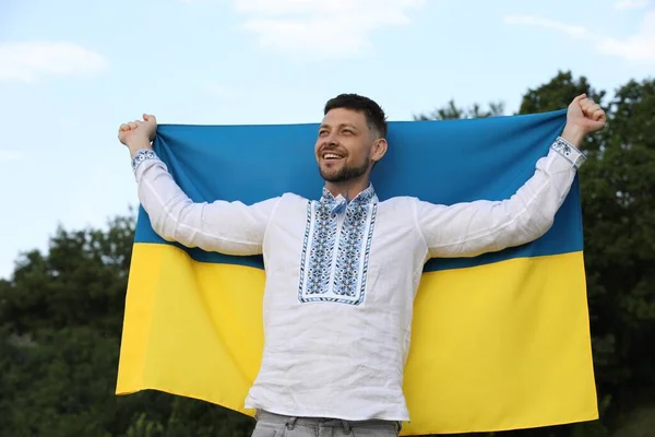 在Vyshyvanka的男子 在户外悬挂乌克兰国旗 — 图库照片