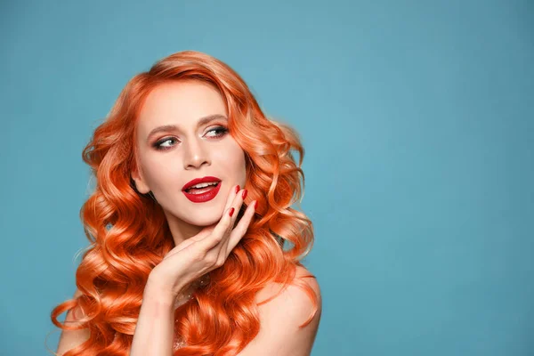 Beautiful woman with long orange hair on light blue background