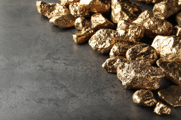 Pile of gold nuggets on grey table, space for text