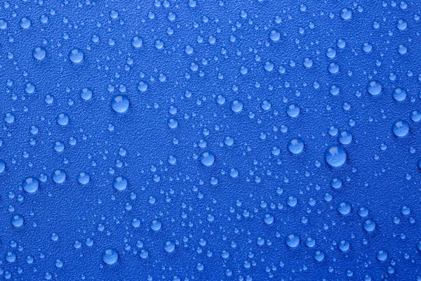 Water drops on blue background, top view