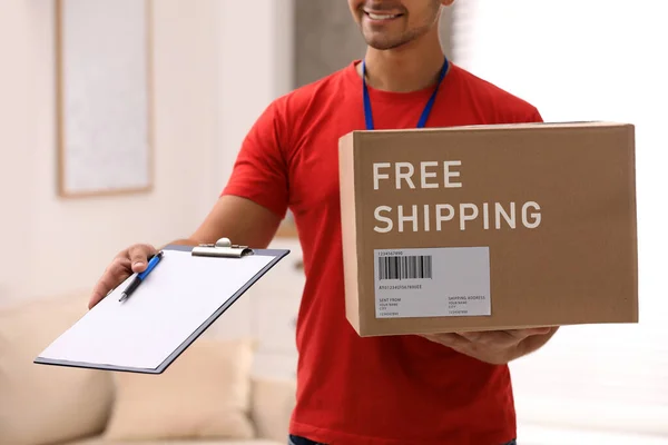 Young Courier Holding Parcel Clipboard Indoors Closeup Free Shipping — Stockfoto